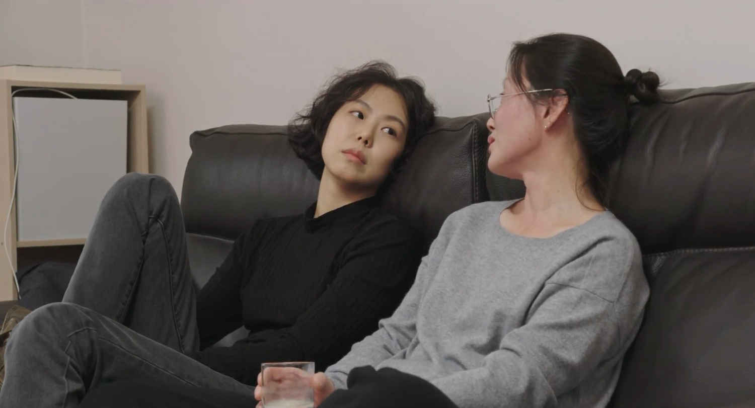 Two women sitting on a couch and looking at each other